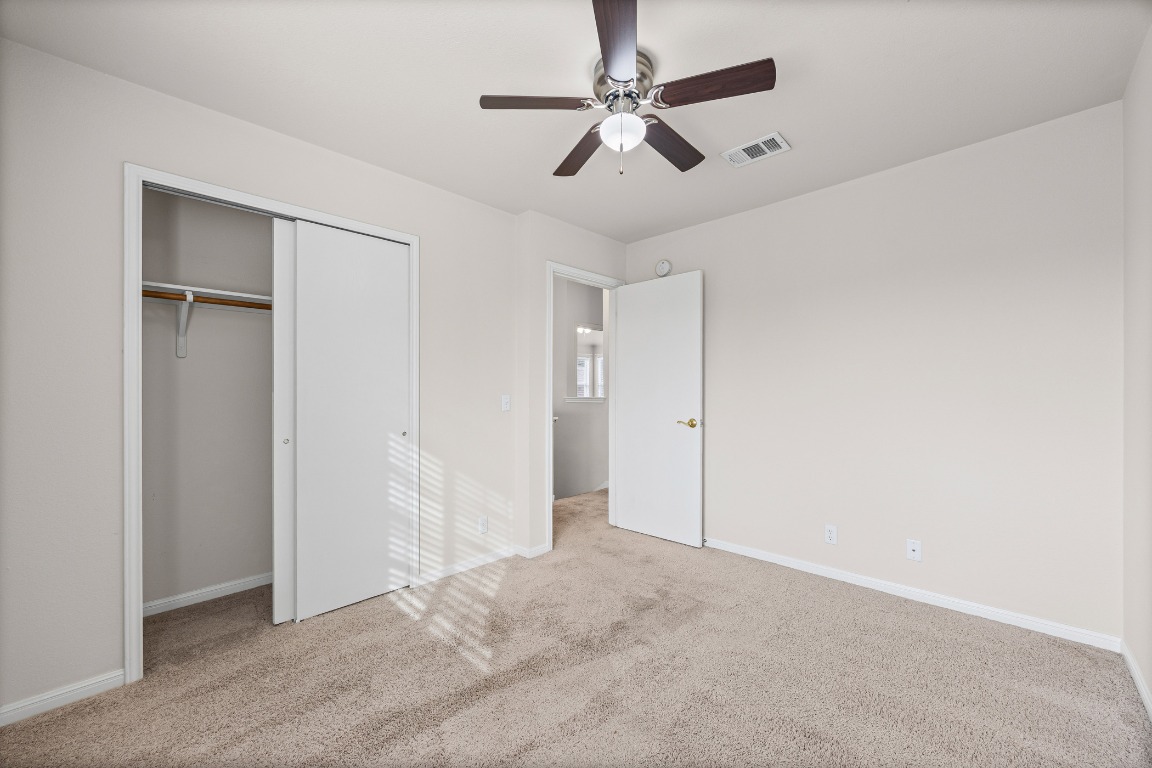 336 Celery Loop Austin, TX 78748 - Photo 14 of 32 Unfurnished bedroom with light carpet, ceiling fan, and a closet