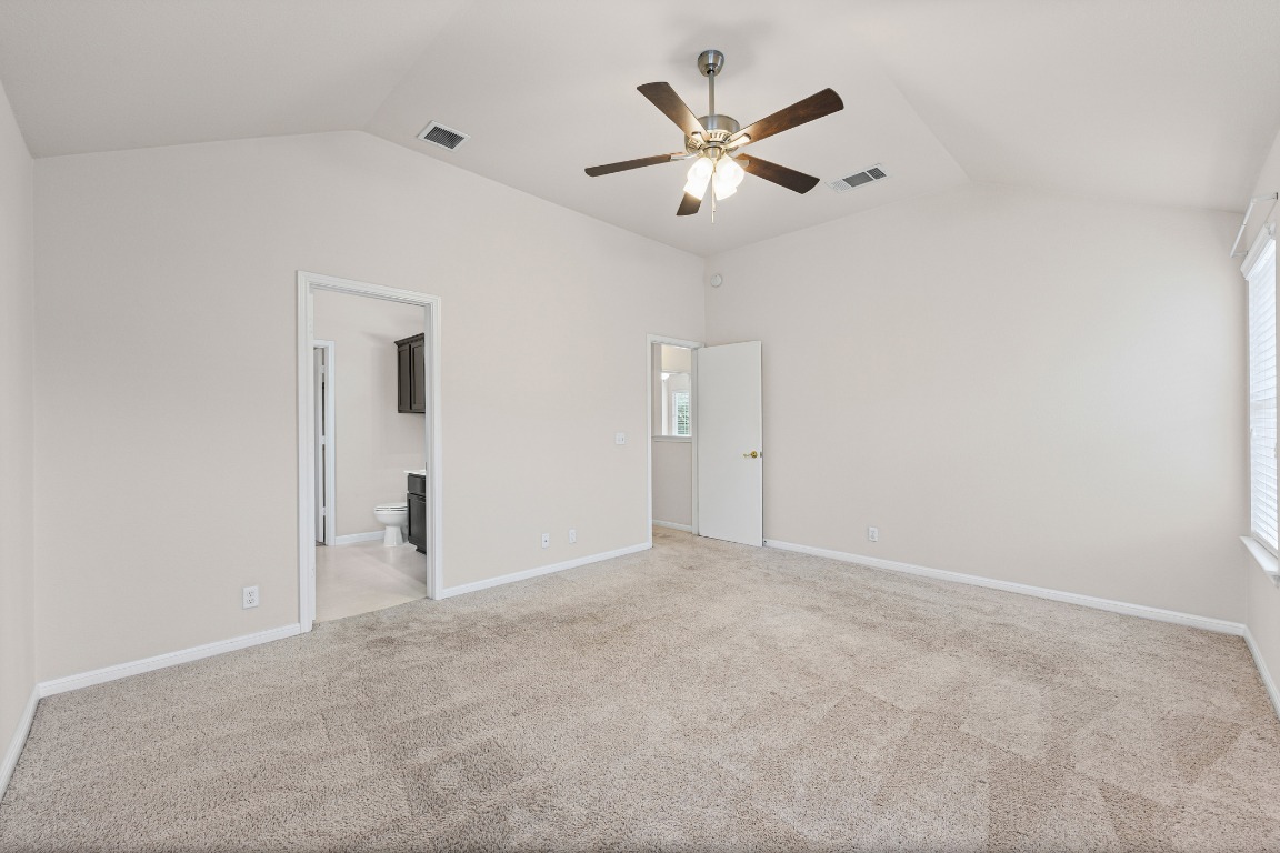 336 Celery Loop Austin, TX 78748 - Photo 17 of 32 Unfurnished bedroom featuring lofted ceiling, light carpet, a ceiling fan, and connected bathroom