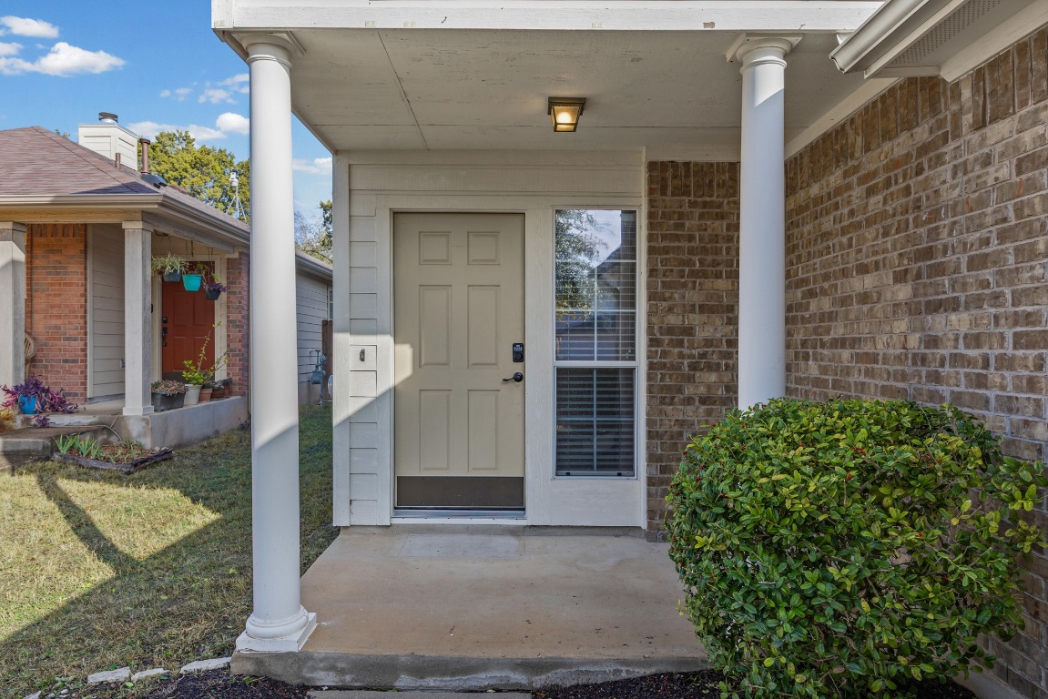 336 Celery Loop Austin, TX 78748 - Photo 2 of 32 Property entrance featuring a porch, brick siding, and a lawn