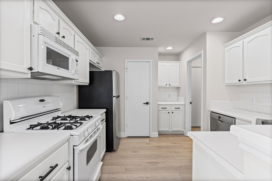 336 Celery Loop Austin, TX 78748 - Photo 3 of 32 Kitchen with white appliances, white cabinets, light countertops, recessed lighting, and light wood-type flooring