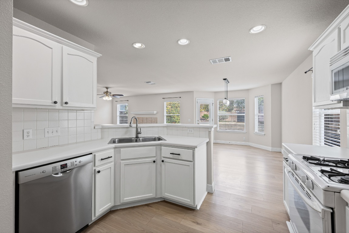 336 Celery Loop Austin, TX 78748 - Photo 4 of 32 Kitchen with a peninsula, dishwasher, white cabinets, light countertops, and recessed lighting