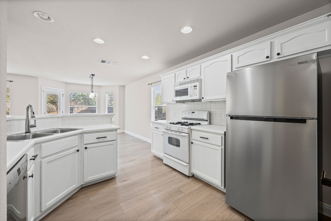 336 Celery Loop Austin, TX 78748 - Photo 5 of 32 Kitchen with appliances with stainless steel finishes, white cabinets, light countertops, recessed lighting, and pendant lighting