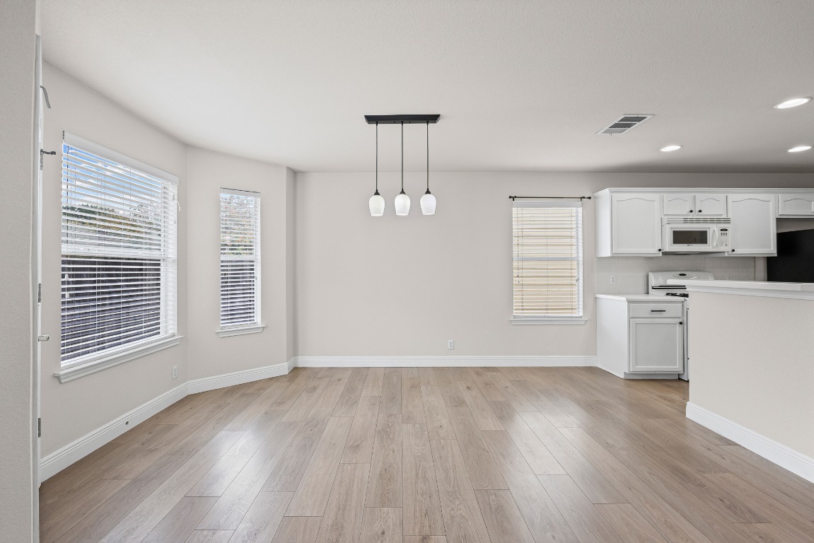 336 Celery Loop Austin, TX 78748 - Photo 6 of 32 Kitchen with white cabinetry, light countertops, light wood-style flooring, hanging light fixtures, and recessed lighting