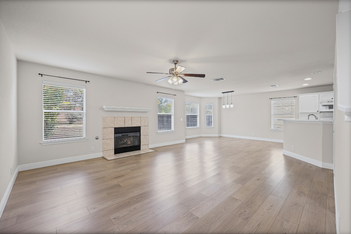 336 Celery Loop Austin, TX 78748 - Photo 7 of 32 Unfurnished living room with a tiled fireplace, light wood-style flooring, ceiling fan, and recessed lighting