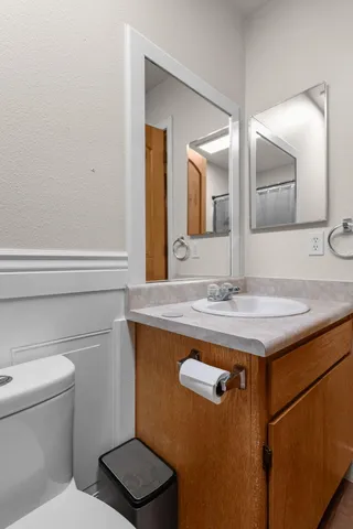 a bathroom with a granite countertop sink a toilet a mirror and vanity