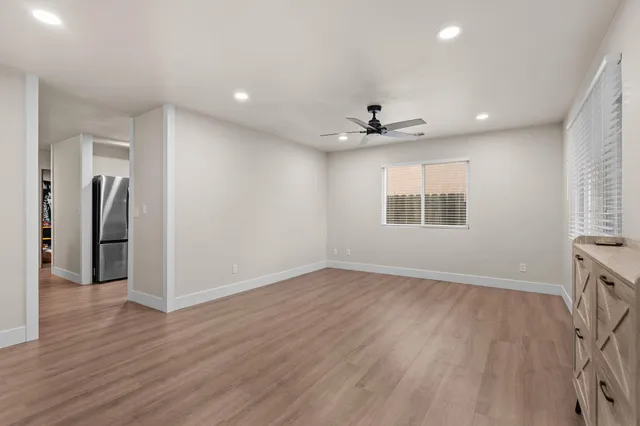 a view of an empty room with a window and wooden floor