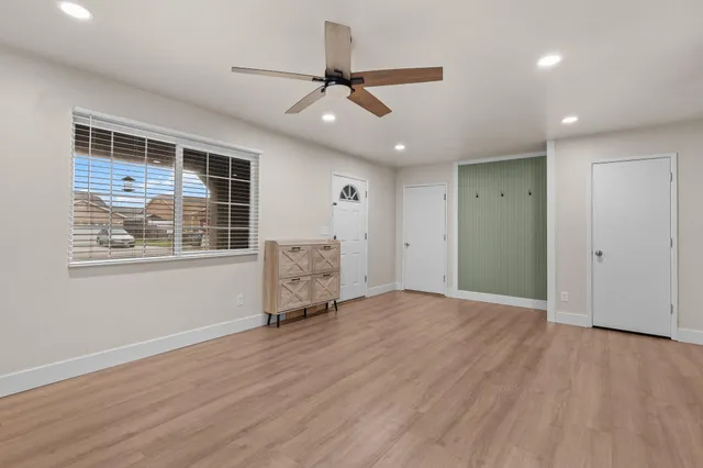 a view of an empty room with a window and wooden floor