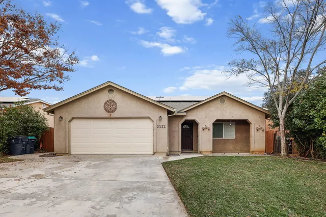 a view of a white house with a yard and large tree