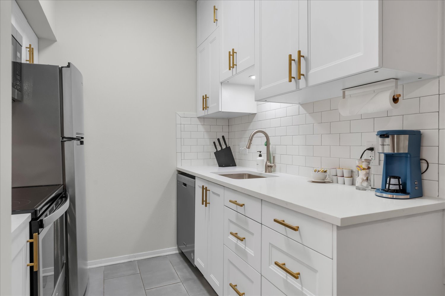 3316 Guadalupe Street, Unit 310 Austin, TX 78705 - Photo 13 of 38 Kitchen featuring appliances with stainless steel finishes, tasteful backsplash, white cabinets, light tile patterned flooring, and light countertops
