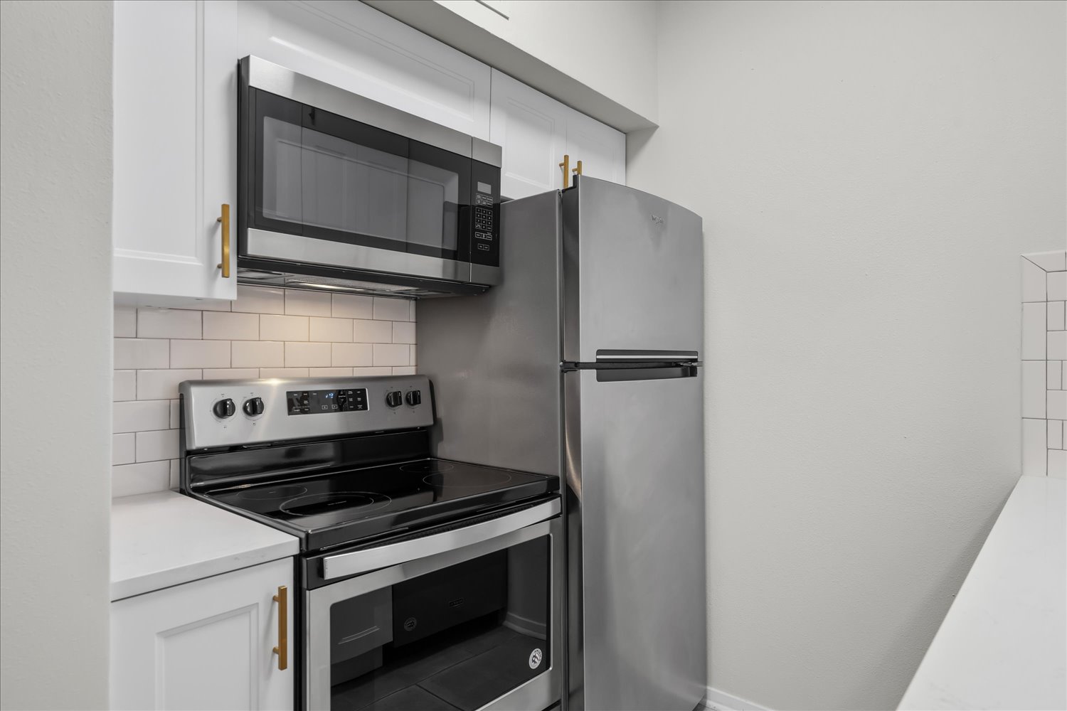 3316 Guadalupe Street, Unit 310 Austin, TX 78705 - Photo 15 of 38 Kitchen with stainless steel appliances, tasteful backsplash, white cabinetry, and light countertops