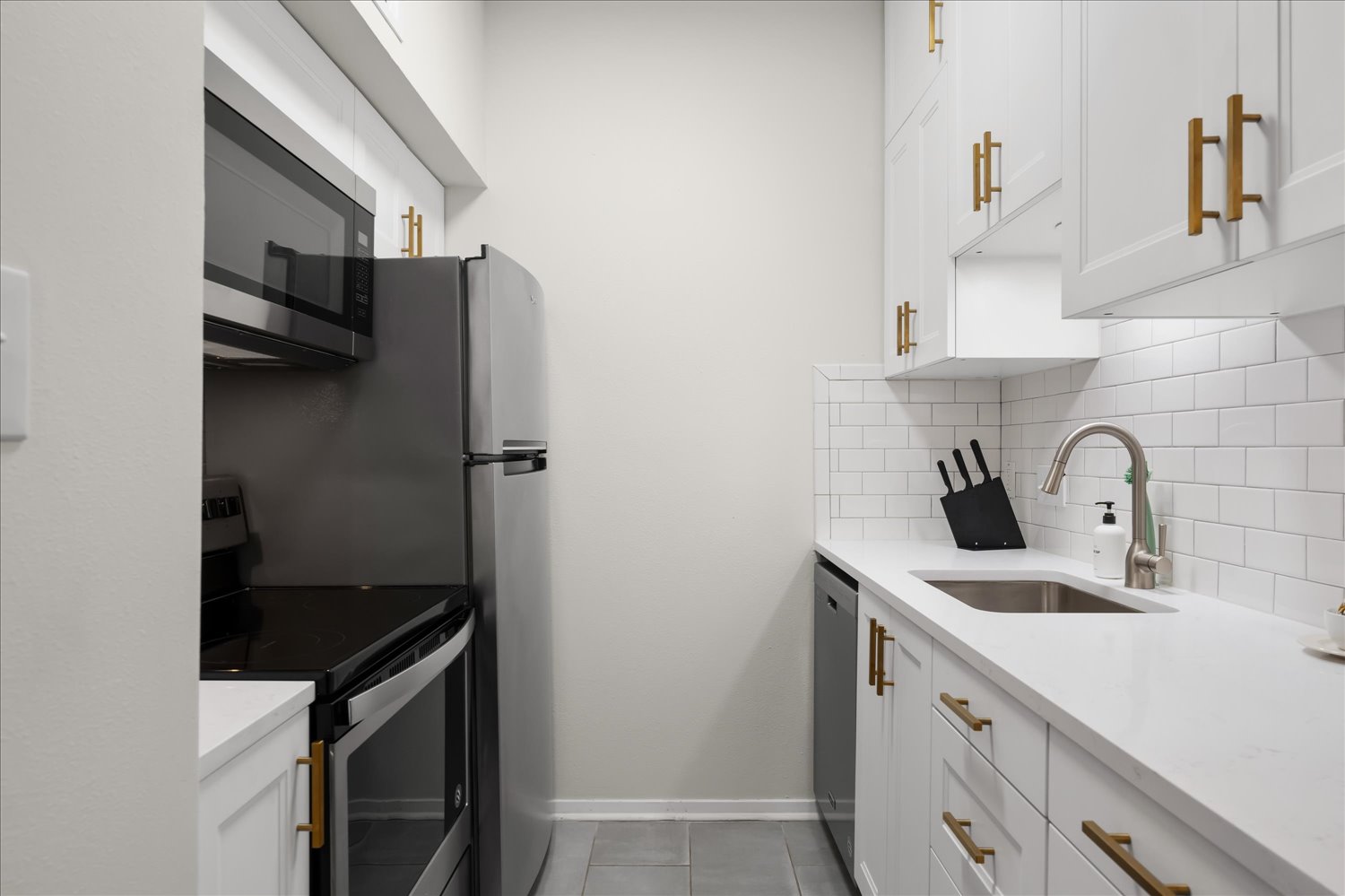 3316 Guadalupe Street, Unit 310 Austin, TX 78705 - Photo 16 of 38 Kitchen featuring appliances with stainless steel finishes, tasteful backsplash, white cabinetry, light tile patterned flooring, and light countertops