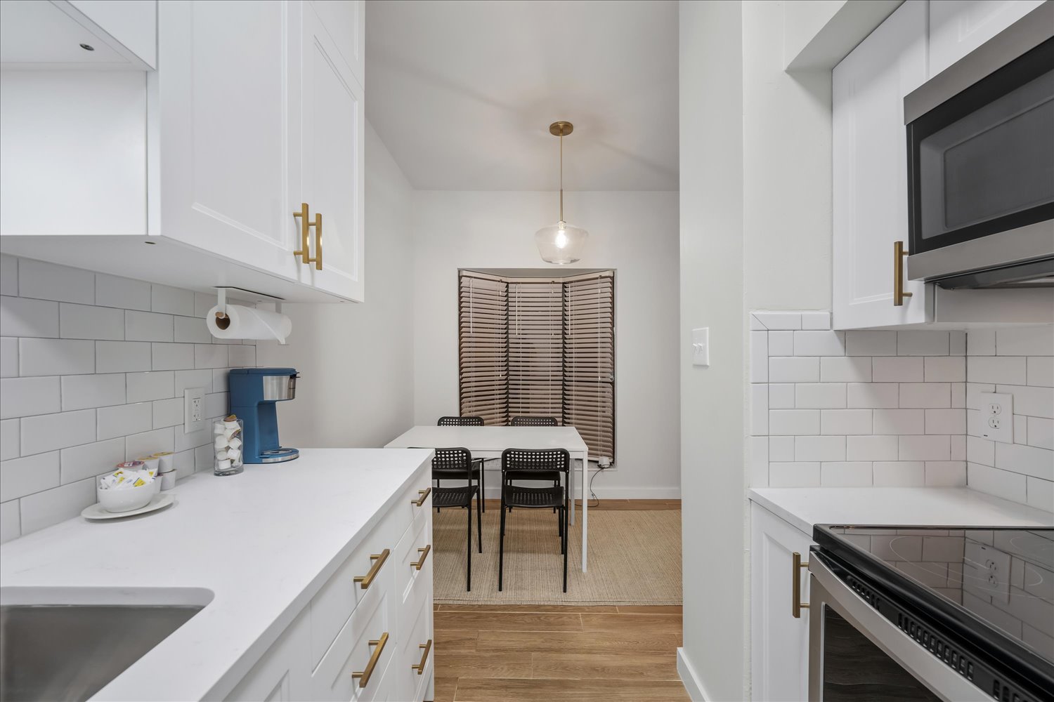 3316 Guadalupe Street, Unit 310 Austin, TX 78705 - Photo 17 of 38 Kitchen with appliances with stainless steel finishes, light wood-style flooring, backsplash, light countertops, and white cabinetry