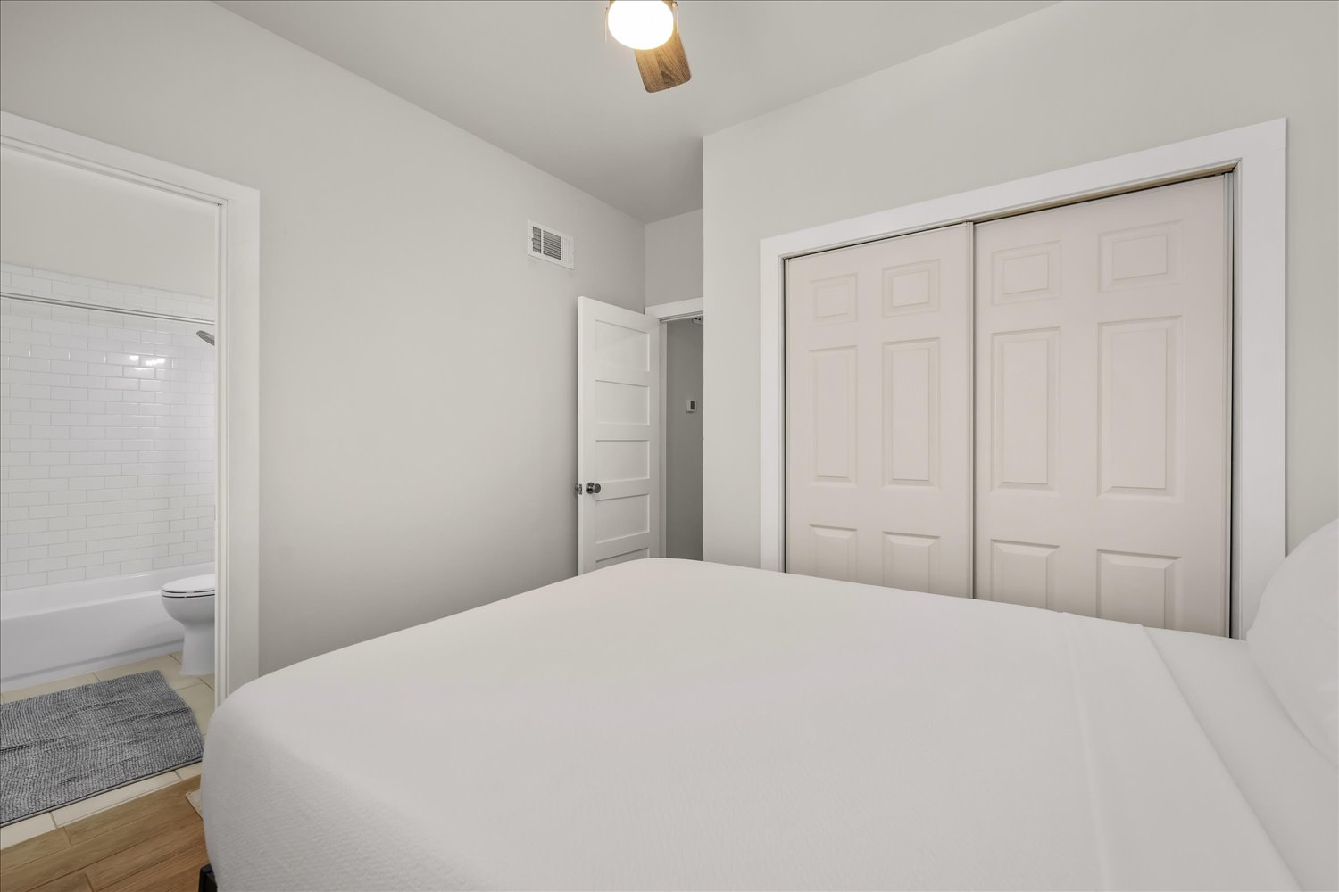 3316 Guadalupe Street, Unit 310 Austin, TX 78705 - Photo 21 of 38 Bedroom featuring a closet, connected bathroom, wood finished floors, and ceiling fan