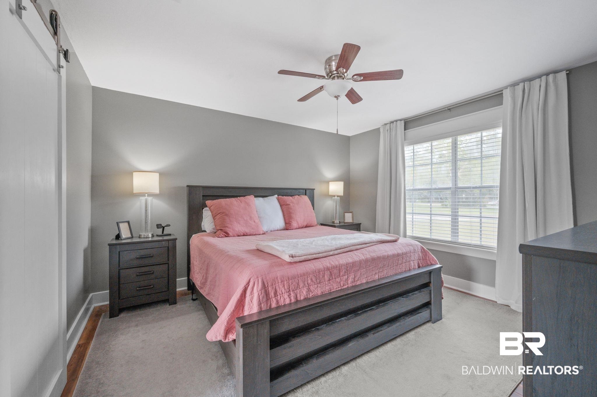 1107 North Oak Street Loxley, AL 36551 - Photo 11 of 40 Carpeted bedroom featuring a barn door and ceiling fan