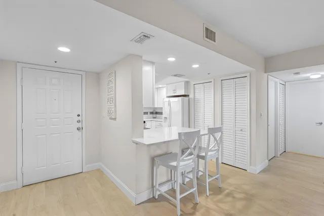 a view of kitchen with refrigerator and white cabinets