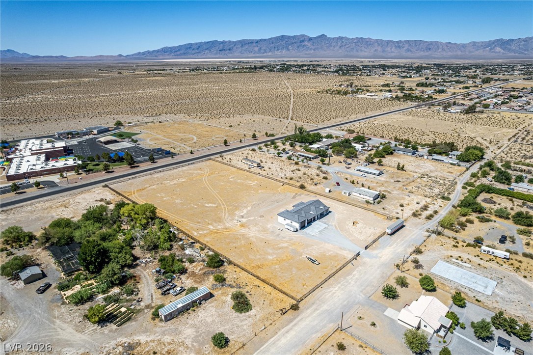 5910 East Kellogg Road Pahrump, NV 89061 - Photo 48 of 58 An aerial perspective reveals a vast desert lot with mountain backdrops and a newly constructed residential building.