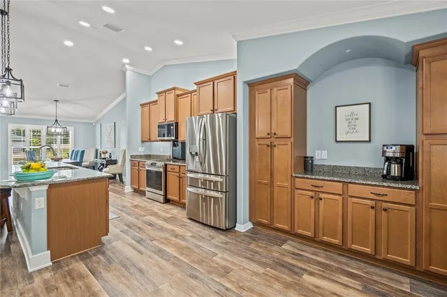 a very nice looking kitchen with granite countertop a stove two sinks a dining table and chairs