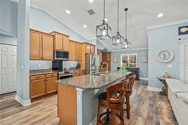 a large kitchen with stainless steel appliances granite countertop a lot of counter space and wooden floor