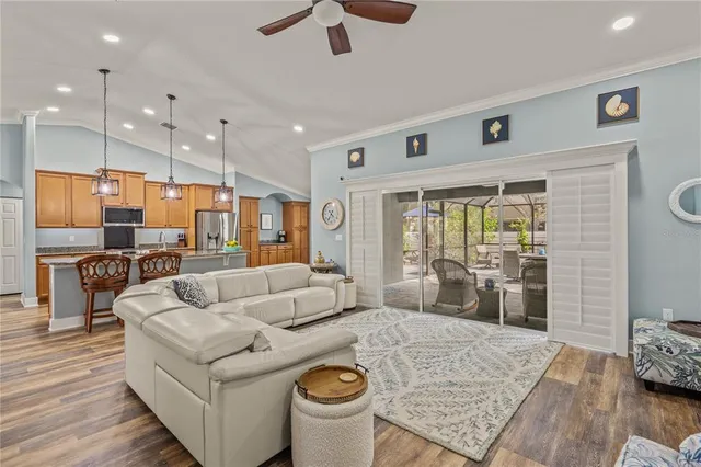 a living room with stainless steel appliances granite countertop furniture wooden floor and a view of kitchen