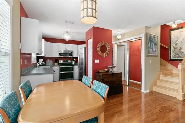 a kitchen with stainless steel appliances kitchen island granite countertop a stove a refrigerator a sink a dining table and chairs with wooden floor