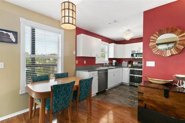 a kitchen with a sink dishwasher a stove a dining table and chairs with wooden floor