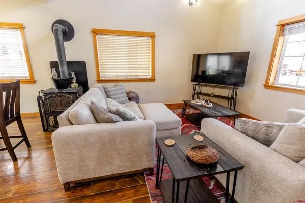 a open kitchen with stainless steel appliances kitchen island granite countertop a refrigerator a stove a dining table and chairs with wooden floor