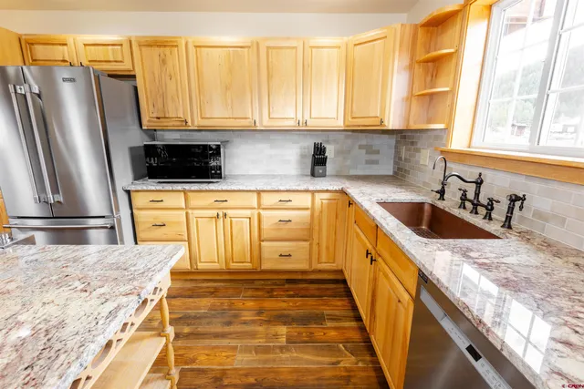 a kitchen with stainless steel appliances granite countertop a sink a stove and a refrigerator