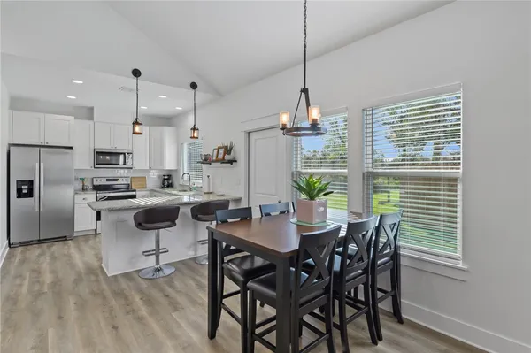 a view of a dining room and livingroom with furniture wooden floor a chandelier