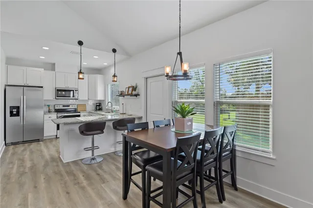a view of a dining room and livingroom with furniture wooden floor a chandelier