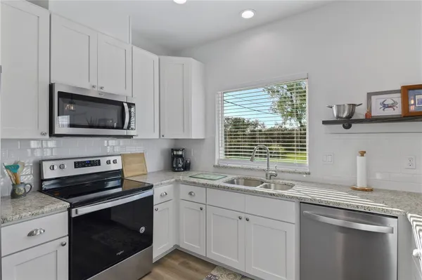 a kitchen with granite countertop a sink cabinets stainless steel appliances and a window