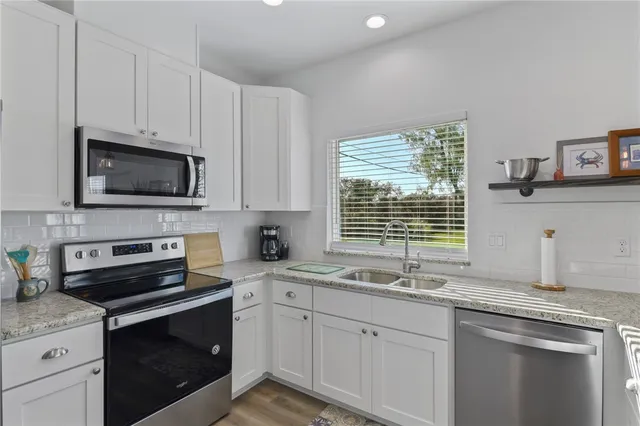 a kitchen with granite countertop a sink cabinets stainless steel appliances and a window