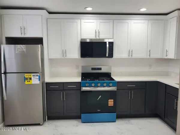a kitchen with stainless steel appliances granite countertop a refrigerator a stove a sink and a microwave