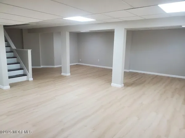 a view of an empty room with wooden floor and stairs