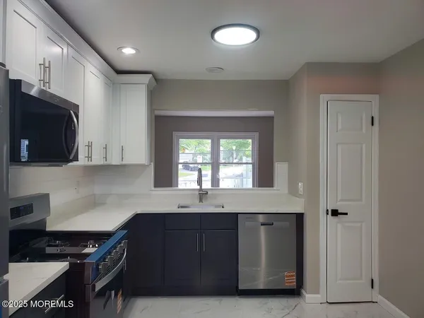 a kitchen with granite countertop a sink cabinets and stainless steel appliances