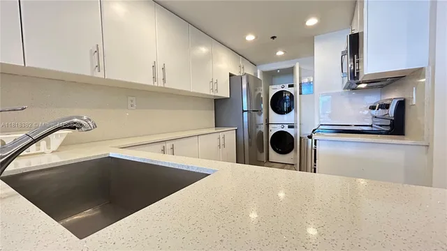 a kitchen with kitchen island a stove a sink and a white cabinets