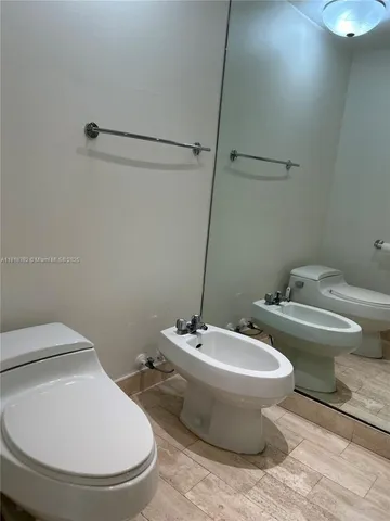 a white toilet sitting next to a bathroom sink and a mirror