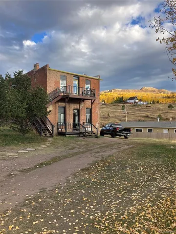 a view of a big house next to a yard with big trees