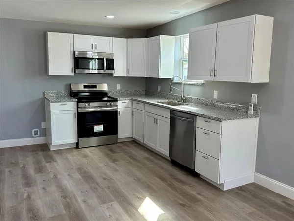 a view of a kitchen with wooden floor a refrigerator a ceiling fan and wooden floor