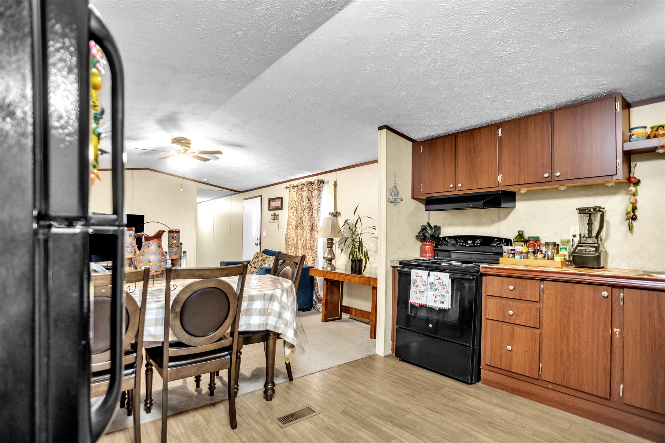 363 El Rey Drive Kyle, TX 78640 - Photo 14 of 40 Kitchen featuring black appliances, wood finish cabinets, light wood-style flooring, a textured ceiling, and ceiling fan