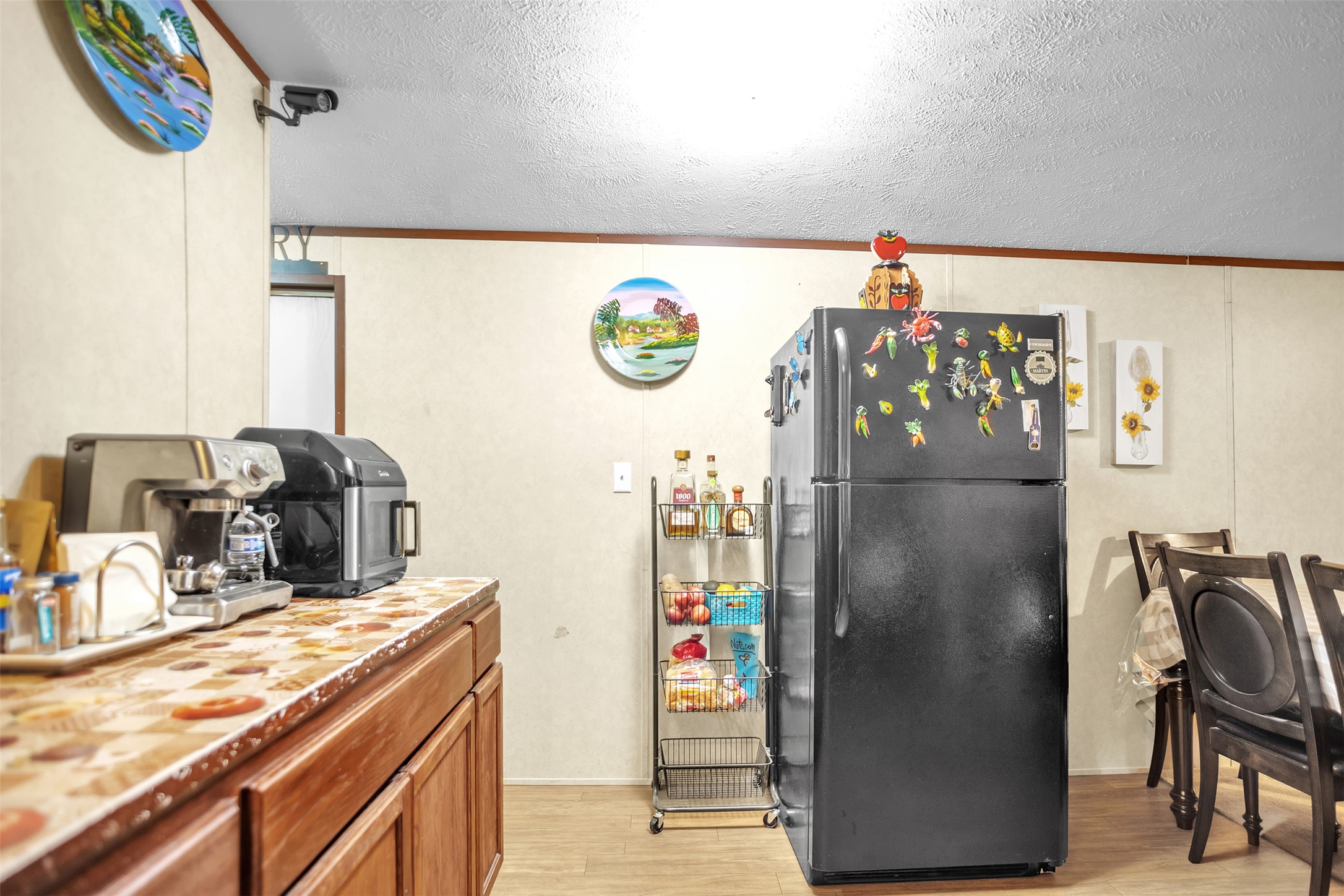363 El Rey Drive Kyle, TX 78640 - Photo 10 of 40 Kitchen featuring freestanding refrigerator, wood finish cabinetry, a textured ceiling, light wood-type flooring, and light countertops