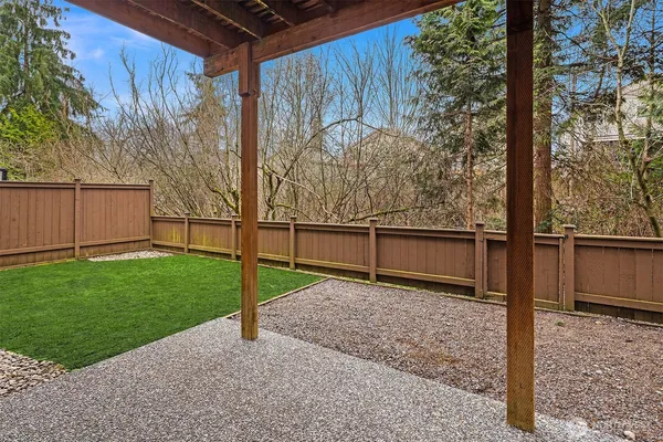 a view of a backyard with wooden fence and a bench