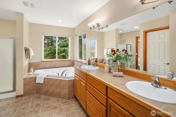 a spacious bathroom with a tub double sink and mirror