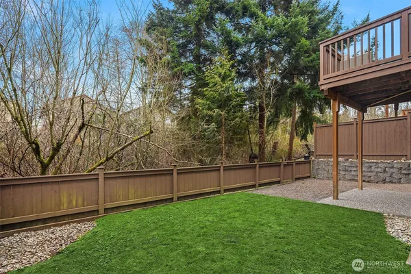 a view of backyard with wooden fence and large trees