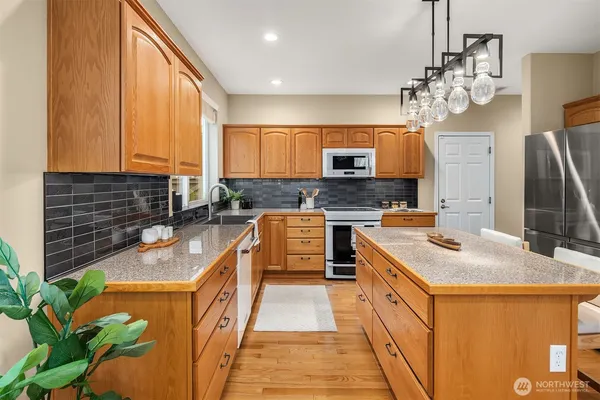 a kitchen with stainless steel appliances granite countertop a sink a stove top oven a counter space and cabinets
