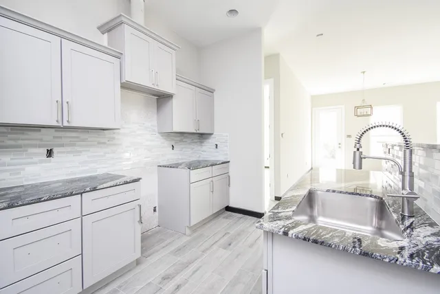 a kitchen with granite countertop white cabinets and sink