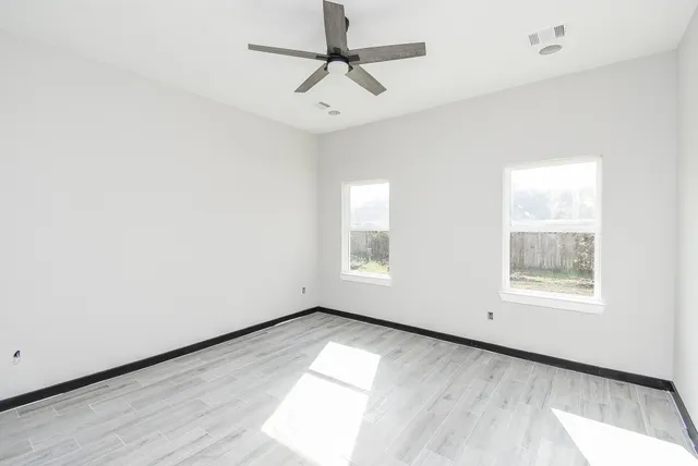 an empty room with a window and a ceiling fan