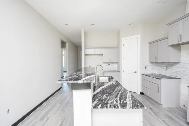 a kitchen with granite countertop a sink stove and cabinets