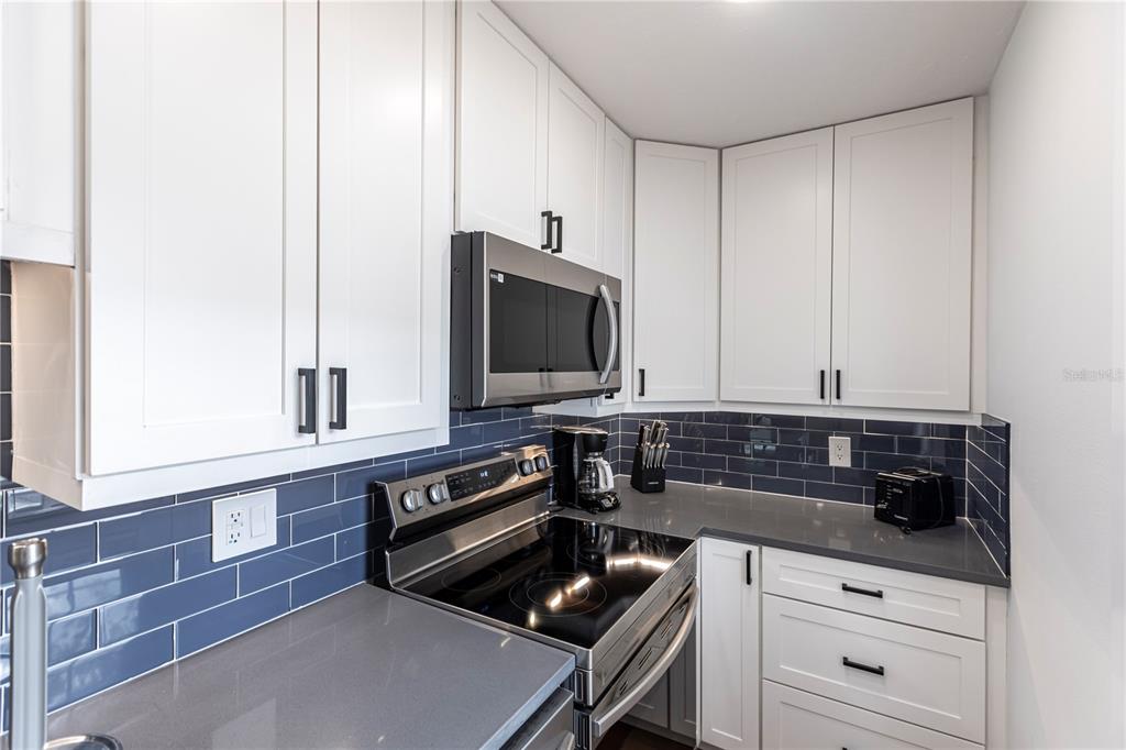 6020 Midnight Pass Road, Unit 48 Sarasota, FL 34242 - Photo 11 of 17 a kitchen with white cabinets and black appliances