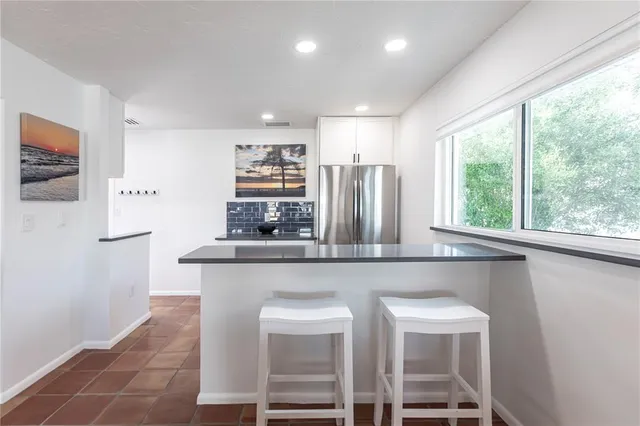 a kitchen with stainless steel appliances a table and chairs in it