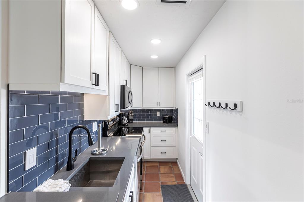 6020 Midnight Pass Road, Unit 48 Sarasota, FL 34242 - Photo 10 of 17 a kitchen with stainless steel appliances a sink a stove top oven a counter space and cabinets